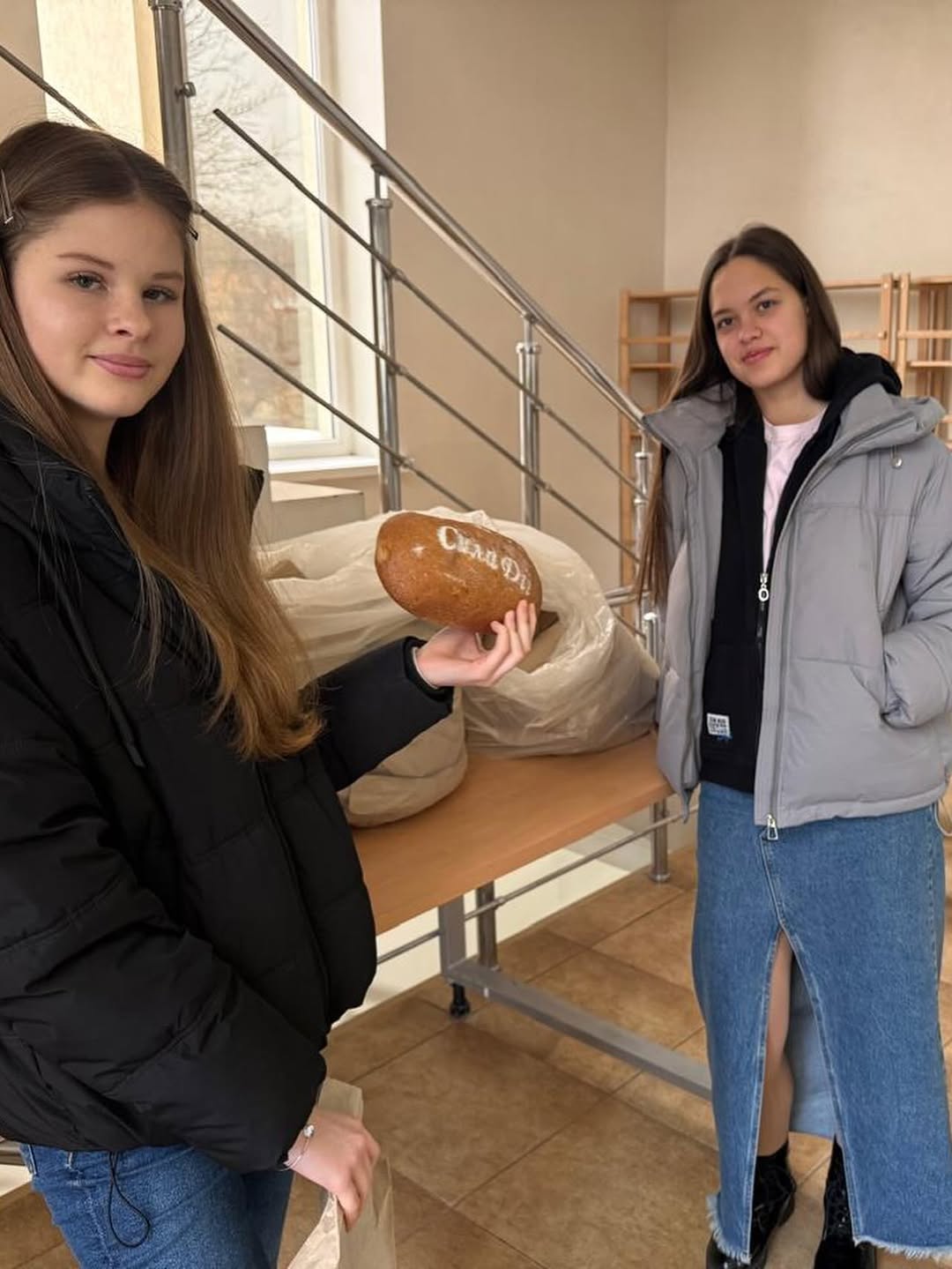 Zwei junge Helferinnen mit frischem Brot für das Projekt 200 Brote pro Woche